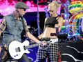 Na scenie występują dwie osoby: muzyk grający na gitarze elektrycznej i wokalistka w dynamicznej pozie.