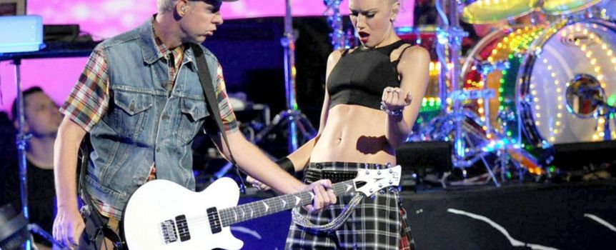 Na scenie występują dwie osoby: muzyk grający na gitarze elektrycznej i wokalistka w dynamicznej pozie.