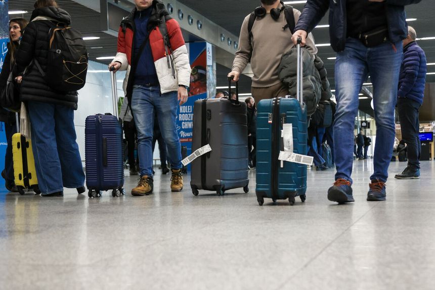 Tłum ludzi na lotnisku ciągnie walizki po posadzce