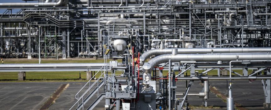Złożona infrastruktura przemysłowa z metalowymi rurami i zasobnikami na tle nieba.