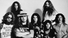 Na zdjęciu grupa mężczyzn z długimi włosami, w stylu lat 70. Zasiadają w różnych pozach.