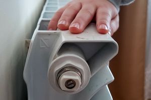 Zbliżenie na rękę dziecka opierającą się na białym grzejniku.