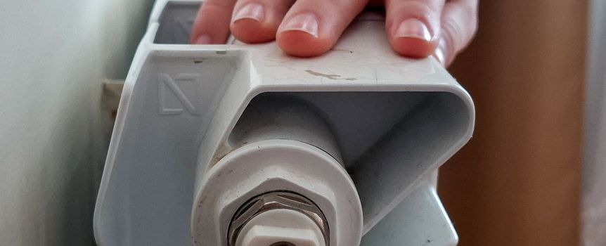 Zbliżenie na rękę dziecka opierającą się na białym grzejniku.