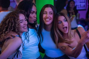 Cztery uśmiechnięte kobiety pozują do selfie na imprezie w kolorowym świetle.