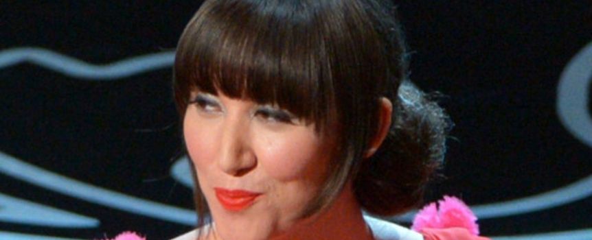 Na zdjęciu uśmiechająca się kobieta w różowej sukience z kwiatowymi akcentami.