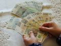 Dwie ręce trzymają banknoty w złotych: 50, 100, 200. Tło z koronką.