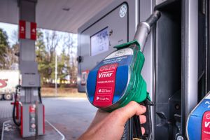 Ujęcie ręki trzymającej dystrybutor paliwa na stacji. W tle widoczny ekran z ceną.