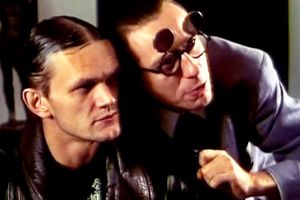 Dwóch mężczyzn w bliskim ujęciu, jeden z okularami, skupiony na rozmowie.