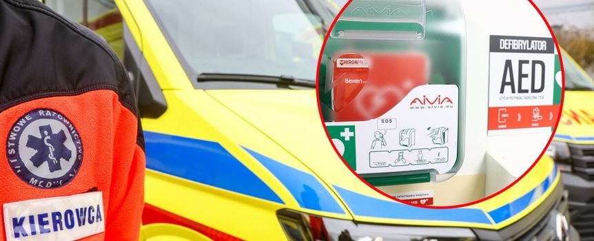 Na zdjęciu widać ratownika medycznego obok karetki oraz defibrylatora AED.
