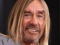 Mężczyzna z długimi, blond włosami i brodą, uśmiechający się, w szarym garniturze.