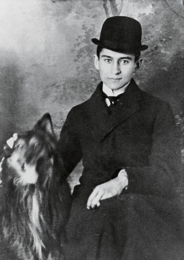 Franz Kafka. Młody mężczyzna w kapeluszu trzyma psa. Tło zdjęcia jest rozmyte, w stylu retro.