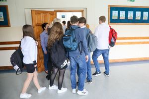 Grupa uczniów wchodząca do sali lekcyjnej, w tle drzwi oraz prace plastyczne na ścianie.