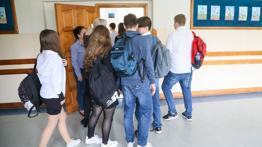 Grupa uczniów wchodząca do sali lekcyjnej, w tle drzwi oraz prace plastyczne na ścianie.