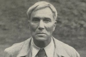 Biało-czarne zdjęcie mężczyzny w jasnym płaszczu, poważna twarz.