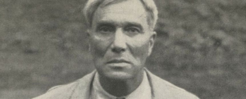 Biało-czarne zdjęcie mężczyzny w jasnym płaszczu, poważna twarz.