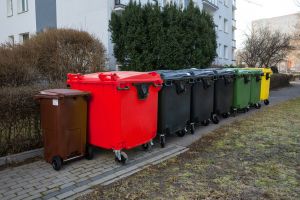 Zbiór kontenerów na odpady w miejskim otoczeniu, różne kolory i rodzaje.