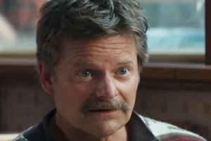 Mężczyzna z krótkimi włosami i wąsem, widoczny w jasno oświetlonym pomieszczeniu.