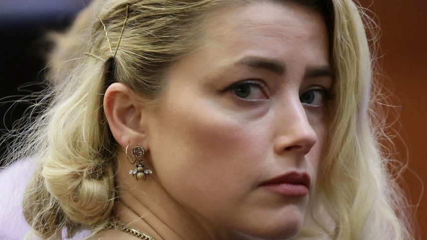 Amber Heard z blond włosami, patrzy z boku, ma na sobie kolczyki w kształcie pszczoły.