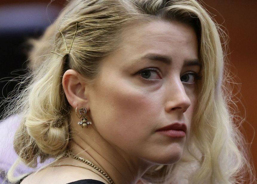Amber Heard z blond włosami, patrzy z boku, ma na sobie kolczyki w kształcie pszczoły.
