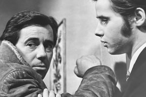 Zdjęcie czarno-białe dwóch mężczyzn; jeden patrzy niepewnie, drugi wygląda na zamyślonego.