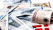 Zestaw banknotów duńskich o różnych nominałach na jasnym tle z małą chorągiewką Danii.