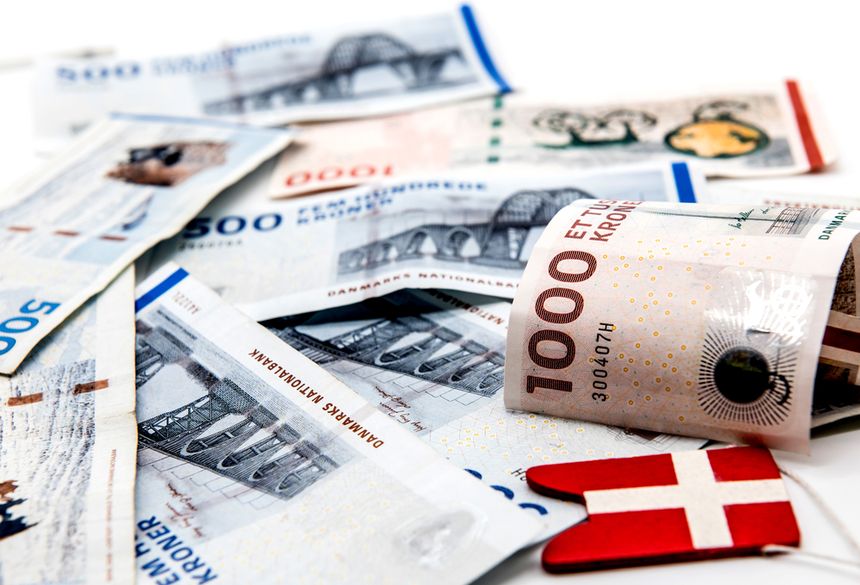Zestaw banknotów duńskich o różnych nominałach na jasnym tle z małą chorągiewką Danii.