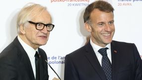Na zdjęciu dwaj mężczyźni w garniturach, uśmiechają się do aparatu. Tło z logo wydarzenia.