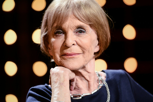 Kobieta z krótkimi włosami, uśmiechającej się na tle migoczących świateł.