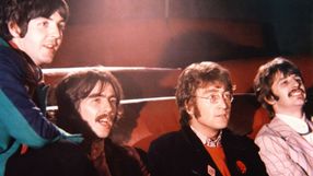 Czterech mężczyzn w kolorowych ubraniach siedzi na kanapie w kinie.