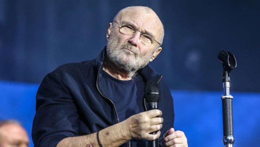 Na zdjęciu starszy mężczyzna z mikrofonem, w ciemnej bluzie, z siwą brodą i okularami.