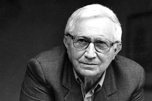 Na zdjęciu starszy mężczyzna w okularach, w szarym garniturze, z krótkimi siwymi włosami.