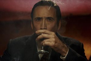 Mężczyzna trzymając kufel wina, siedzi w przyciemnionym wnętrzu, wokół delikatny dym.