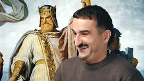 Mężczyzna w swetrze uśmiecha się, w tle postać króla w złotej koronie i szacie.