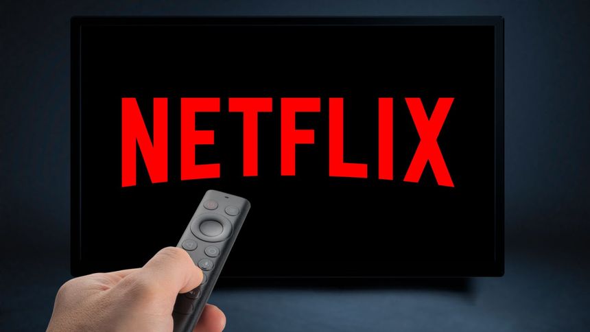 Zdalny pilot trzymany w ręku, na ekranie wyświetla logo Netflix w czerwonym kolorze.
