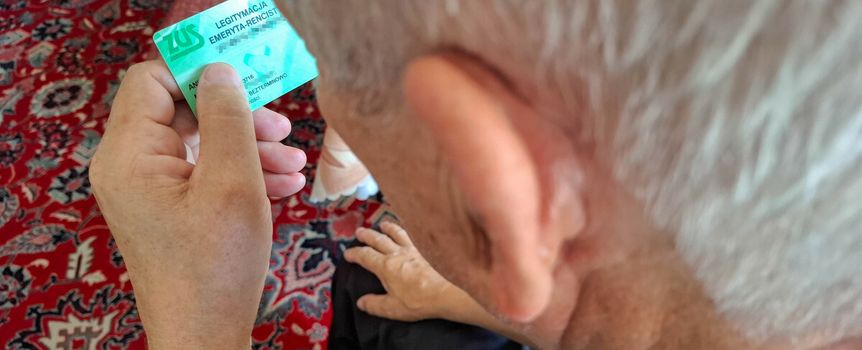 seniorka trzyma legitymację emeryta-rencisty