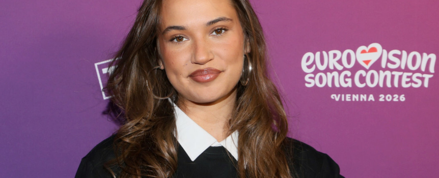 Dziewczyna w czarnej koszulce, na tle fioletowym, uśmiechnięta.