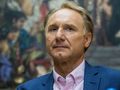 Mężczyzna w jasnej koszuli i granatowym żakiecie, poważnie spogląda w stronę kamery.