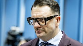 Łukasz Mejza w garniturze. Tło w odcieniach niebieskiego.