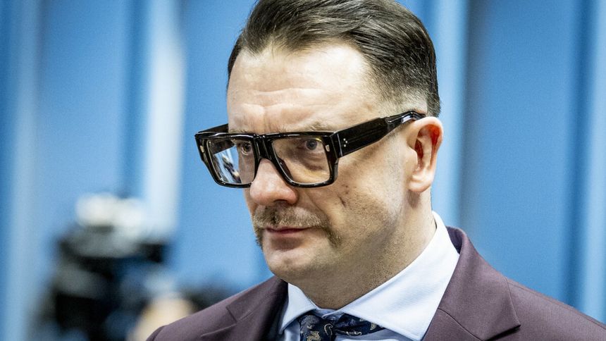 Łukasz Mejza w garniturze. Tło w odcieniach niebieskiego.