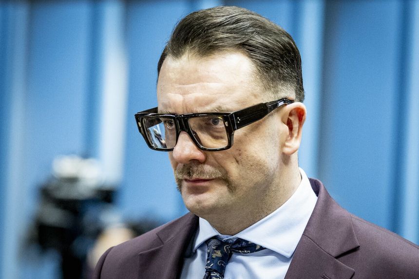 Łukasz Mejza w garniturze. Tło w odcieniach niebieskiego.