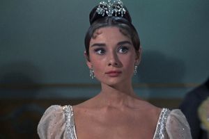 Na zdjęciu młoda kobieta w eleganckiej sukni wieczorowej, z diademem na głowie i delikatnym makijażem.
