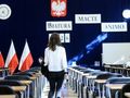 Kobieta w białej bluzce idzie do sali maturalnej, w tle polskie flagi i napisy 