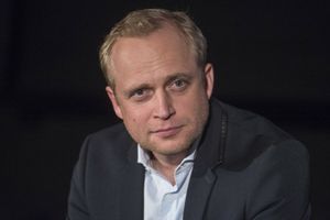 Na zdjęciu mężczyzna w granatowej marynarce, z krótkimi blond włosami, patrzy w obiektyw.