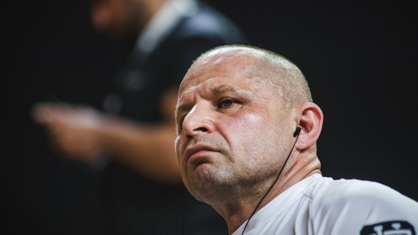 Jacek Murański w białej koszulce, słuchający muzyki, z wyrazem skupienia na twarzy.