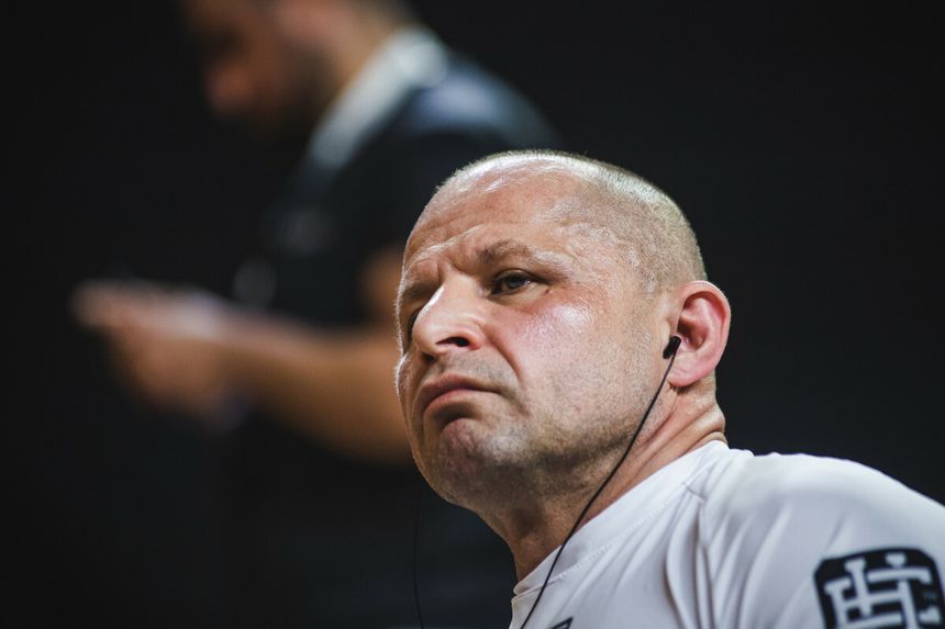 Jacek Murański w białej koszulce, słuchający muzyki, z wyrazem skupienia na twarzy.