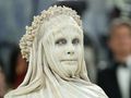 Na zdjęciu Heidi Klum w białej masce i drapowanej tkaninie, z kwiatowym wieńcem na głowie.