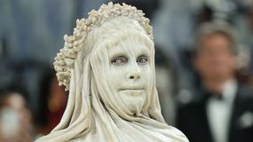 Na zdjęciu Heidi Klum w białej masce i drapowanej tkaninie, z kwiatowym wieńcem na głowie.