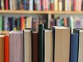 Zbliżenie na rząd zamkniętych książek w bibliotece, w tle nieczytelne powieści.