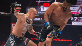 Dwóch zawodników MMA w trakcie walki w klatce, intensywne wymiany ciosów.