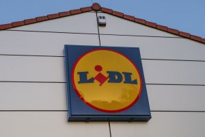 Logo sieci sklepów Lidl na ścianie budynku, w tle błękitne niebo.